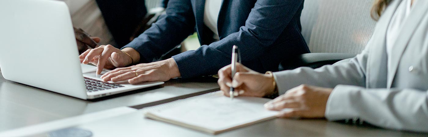 Two people work together on computers and note pads