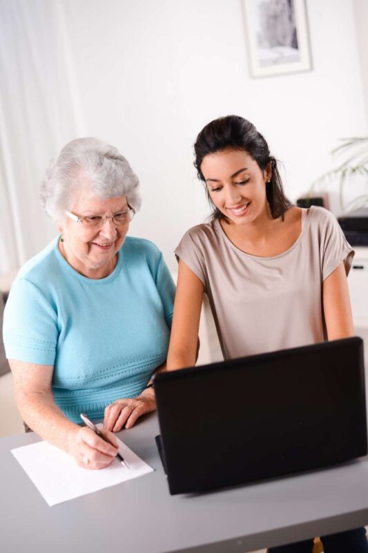 A volunteer helps a senior with computer work